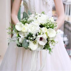 a bride holding a bouquet of white flowers