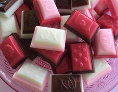 a pink plate topped with lots of different types of chocolates on top of each other