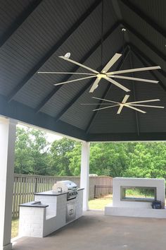 an outdoor kitchen with grill and ceiling fan