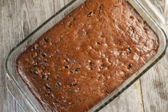 a loaf of chocolate cake sitting in a glass dish on top of a wooden table