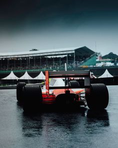 a red race car driving down a wet track