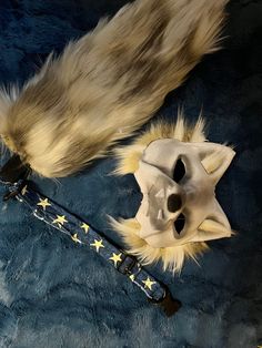 an animal's tail and mask are laying on a blue surface with stars around it