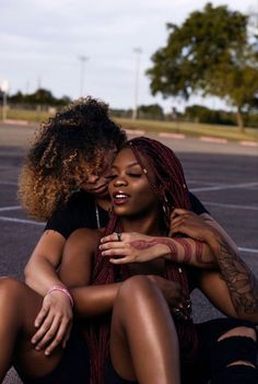 two women sitting on the ground hugging each other