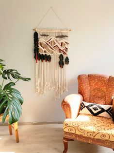 a living room with a chair, potted plant and macrame wall hanging