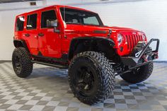 a red jeep is parked in a garage