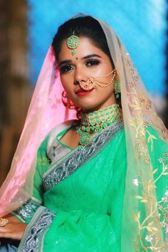 a woman in green and gold is posing for the camera with her veil draped over her head