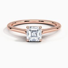 a rose gold engagement ring with an emerald cut diamond in the center, on a white background