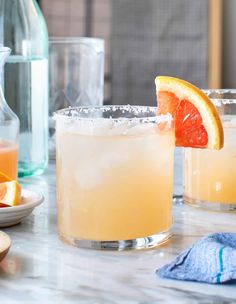 two glasses filled with orange juice and garnished with an orange slice on the rim