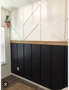 an empty room with black and white paneling on the walls, potted plant hanging from the ceiling