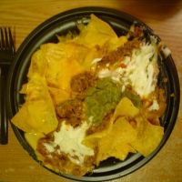 a black plate topped with nachos next to a fork