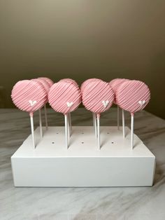 four pink heart shaped lollipops sitting on top of a white stand