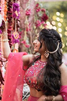 a woman in a pink sari is holding up a mirror with lights behind her