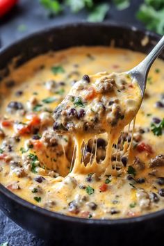 a ladle full of cheeseburger soup being held up by a fork over it