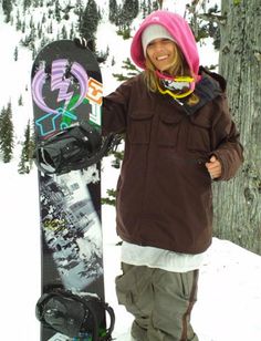 a woman standing in the snow with her snowboard