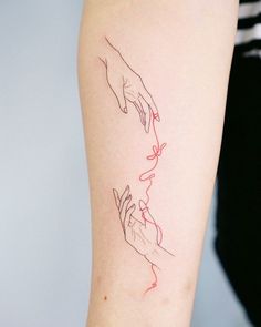 two hands touching each other with red ink on the left side of the arm tattoo