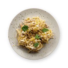 a white plate topped with pasta covered in sauce and garnished with parsley