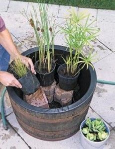 a man kneeling down next to a barrel filled with plants