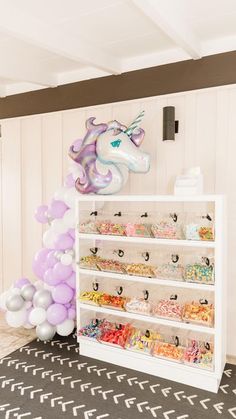 an unicorn themed birthday party with balloons and desserts on the shelves in front of it