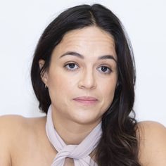 a woman with long hair wearing a neck tie and looking off to the side, in front of a white background