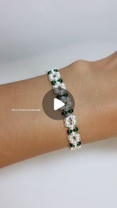 a woman's arm wearing a bracelet with white and green beads