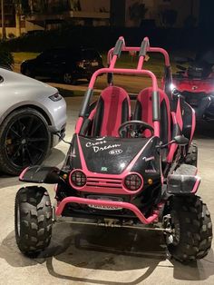 a pink and black three wheeled vehicle parked in a parking lot next to a silver car