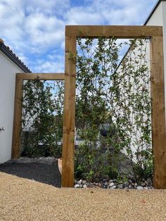 a wooden frame sitting next to a white building with plants growing out of it's sides