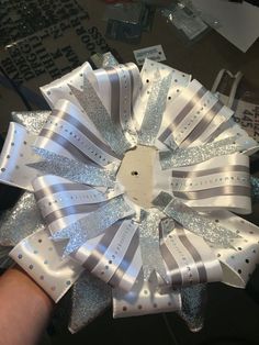 an image of someone's hand holding a white and gray ribbon with silver sequins on it