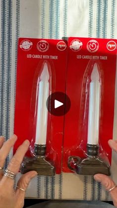 two candles are being held up in front of each other with the box on top