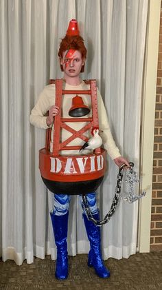 a man dressed up as david the clown holding a chain and wearing blue rubber boots