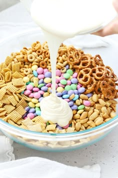 a bowl filled with cereal and pretzels being drizzled with milk