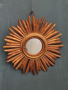 a gold sunburst mirror hanging on a wall