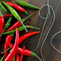 several red and green peppers on a wooden table next to an earphone cord with wires attached