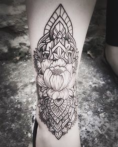 a black and white tattoo on the leg of a woman's legs with flowers