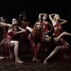 a group of women in red dresses and fringes posing for the camera with their hands on their head