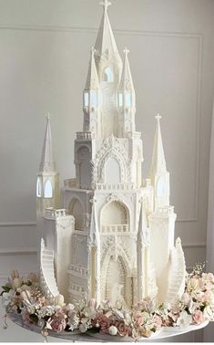 a cake that is shaped like a castle with flowers on the side and lights at the top