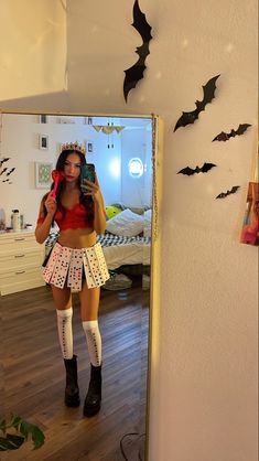 a woman taking a selfie in front of a mirror with bats on the wall