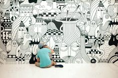 a person kneeling down in front of a wall with black and white designs on it