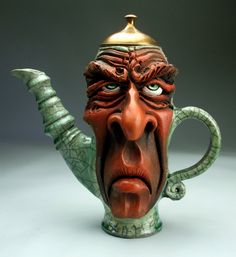 a ceramic teapot with a face and horns on it