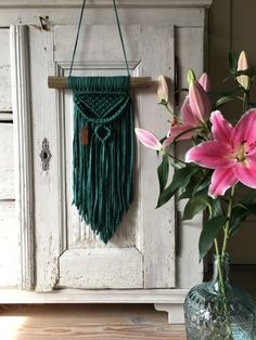 a vase filled with pink flowers sitting next to a white wall hanging on a door