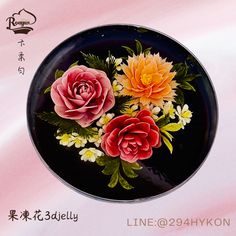 three flowers painted on a black plate with chinese writing in the bottom right hand corner