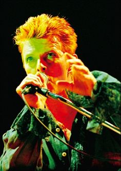 a man with red hair is singing into a microphone