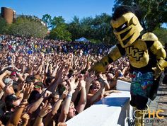 a man in a yellow costume standing on top of a stage surrounded by people holding their hands up