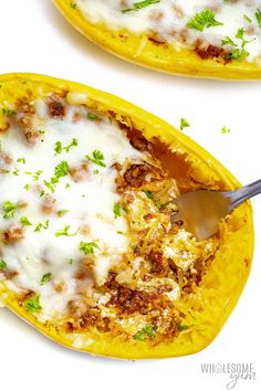 two stuffed yellow peppers with cheese and parsley on top, one has a spoon in it