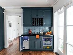 a kitchen with dark blue cabinets and wood flooring, an icebox cooler is in the corner