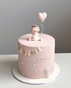 a pink cake decorated with a baby's first birthday decoration