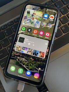 an iphone is plugged into a charger on top of a laptop computer keyboard