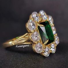 an emerald and white diamond ring on a black surface