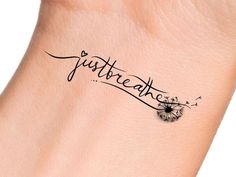 a tattoo on the wrist that says just breathe and dandelions are flying in the air