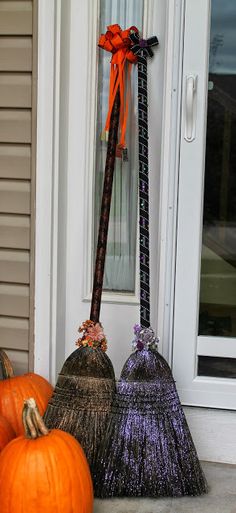 two brooms sitting on the front porch next to pumpkins