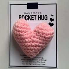 a pink crocheted heart shaped brooch on a white card with the words handmade pocket hug written below it